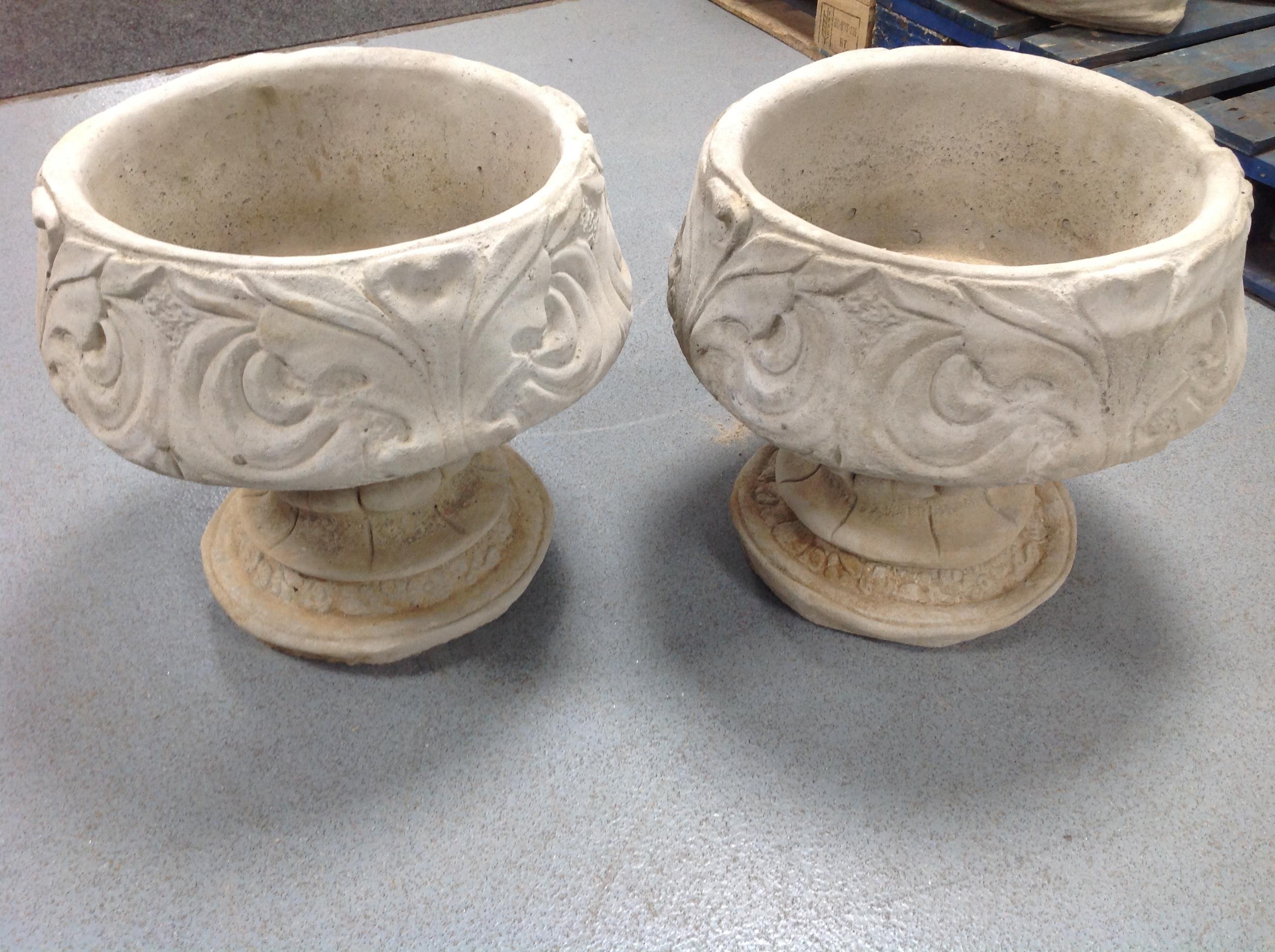 A pair of concrete urns on stands