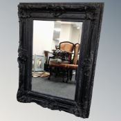 A traditional style overmantel bevelled mirror in heavy black frame