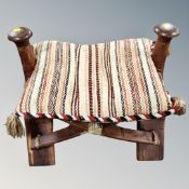 A hardwood camel stool with cushion seat
