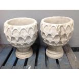 A pair of concrete pineapple urns on stands