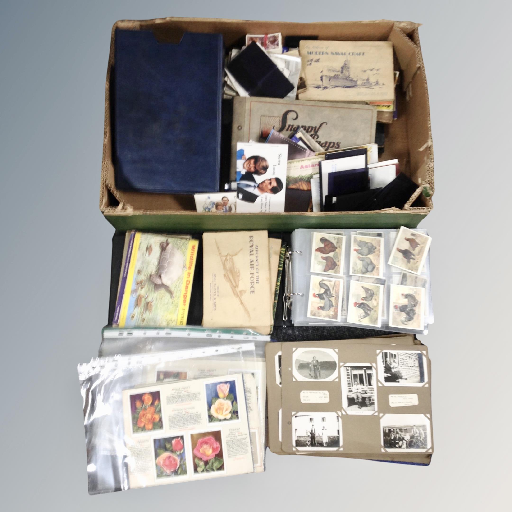 A box of 20th century monochrome and colour postcards, cigarette and tea cards,