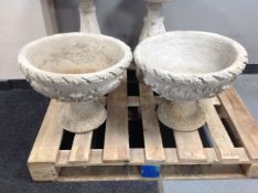 A pair of concrete acanthus urns on stands