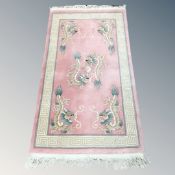 A Chinese dragon patterned rug on pink ground,