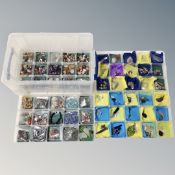 A plastic storage box with four compartmental trays containing pendants on chains,