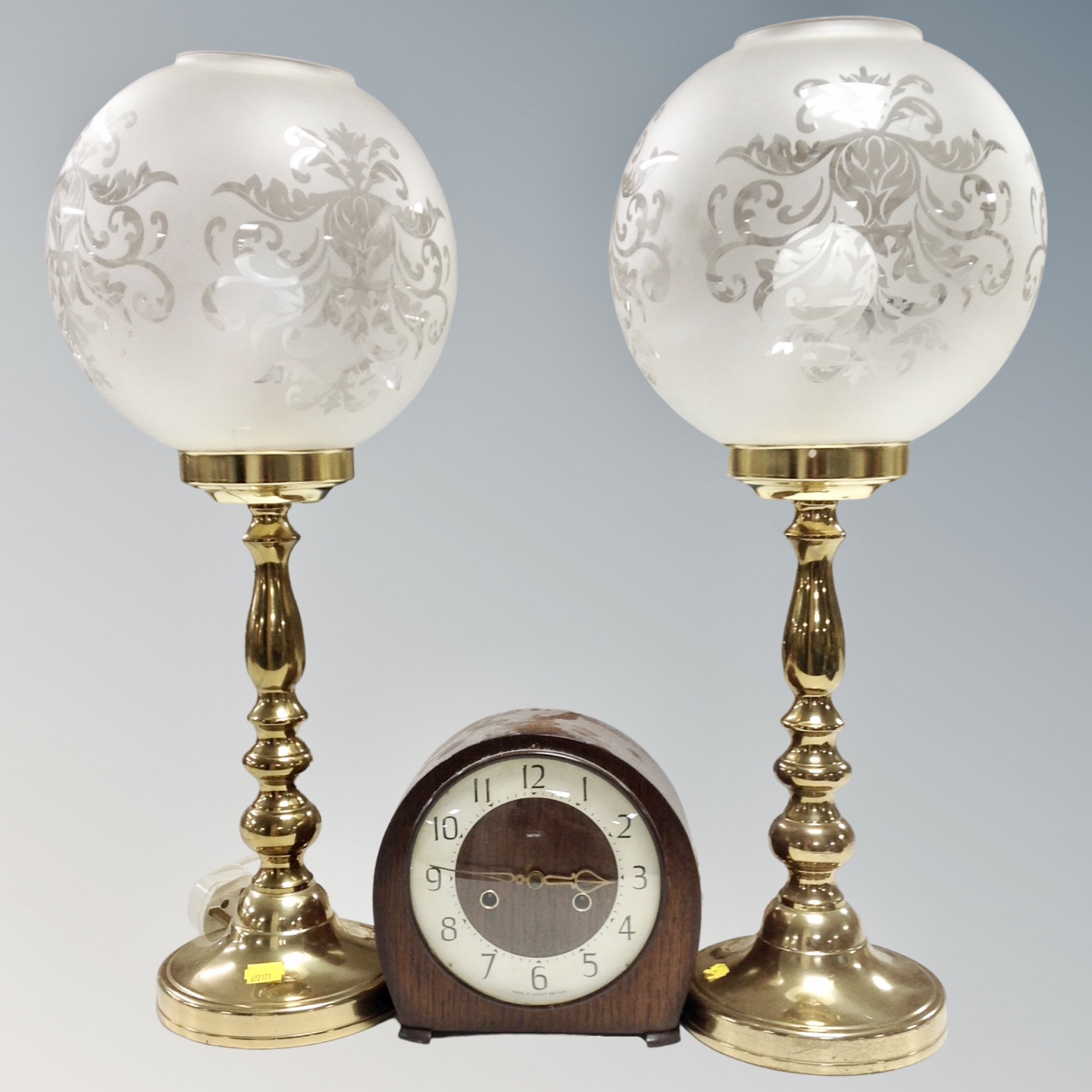 A pair of brass table lamps with glass ball shades together with an oak cased Smiths mantel clock
