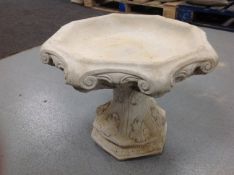 A concrete octagonal bird bath