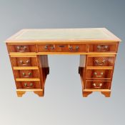 A yew twin pedestal desk fitted with nine drawers and green leather top
