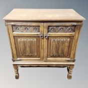 An oak linen fold cabinet on raised legs