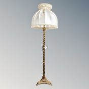 An ornate brass barley twist column standard lamp on paw feet with silk shade