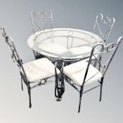 A contemporary circular glass topped dining table on metal base together with four matching chairs