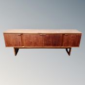 A Stonehill Furniture teak four door low sideboard fitted with central drawers and cocktail cabinet