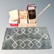 A vintage woolen rug and two boxes containing framed pictures, marquetry panels, art supplies,