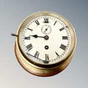 A circular brass ship's timepiece with key, overall diameter 22cm.