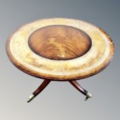 A circular mahogany coffee table on four-way pedestal with leather inset panel