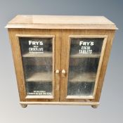 An oak double door glazed bookcase on bun feet with advertisement 'Fry's milk chocoloate',