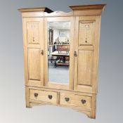 An Art Nouveau oak double door wardrobe with mirrored panel door