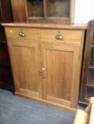 An antique pine double door cupboard fitted with two drawers