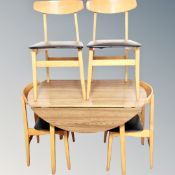 A mid century drop leaf kitchen table together with four chairs in teak finish