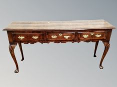 A George III inlaid walnut dresser base fitted with three drawers with brass drop handles,