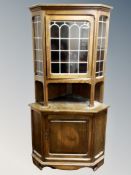 An oak corner cabinet with leaded glass panels,