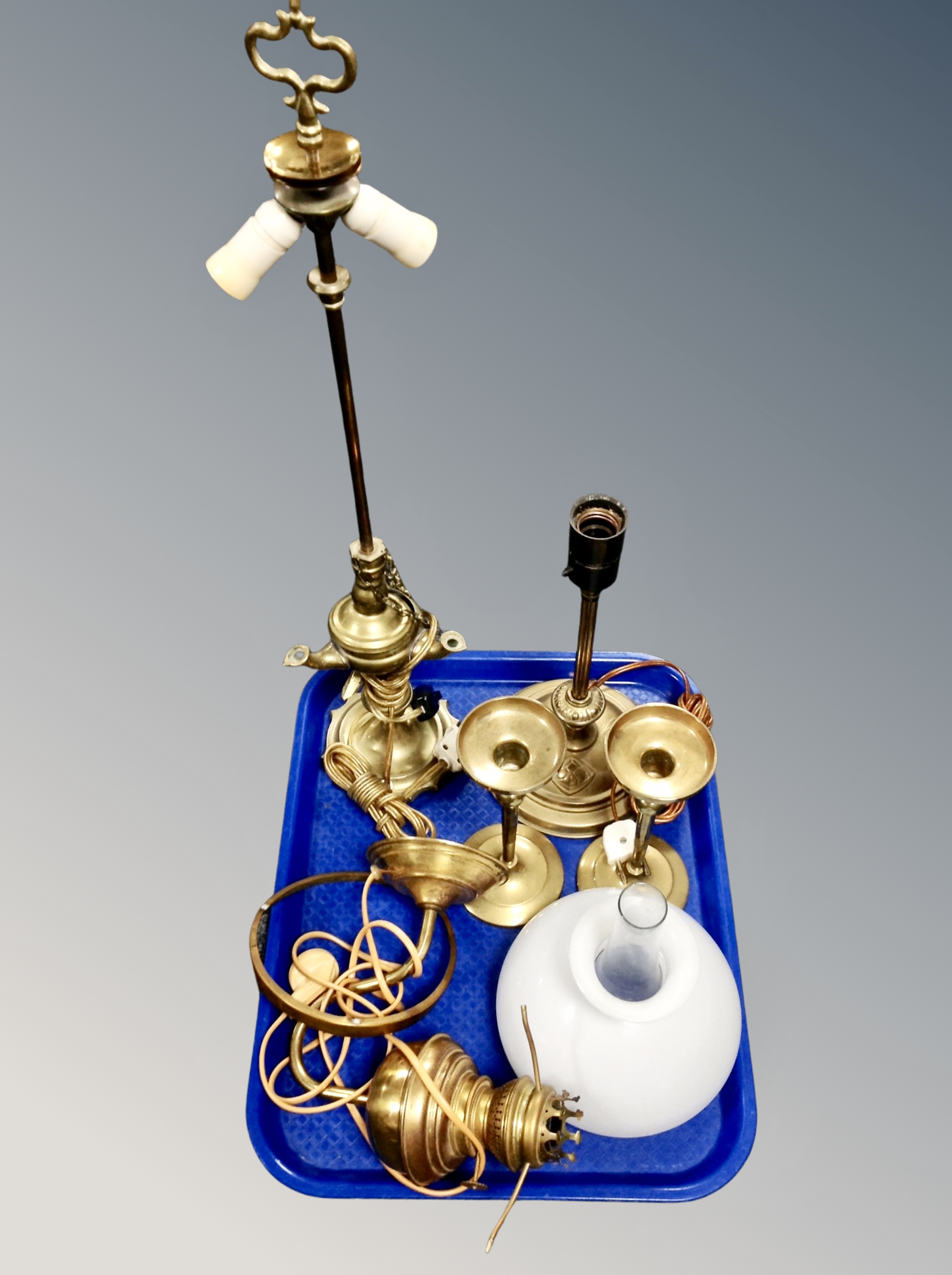 A tray containing three brass converted lamps and a pair of candlesticks.