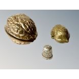 A silver thimble, contained in two graduated brass boxes in the form of walnuts.
