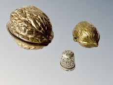 A silver thimble, contained in two graduated brass boxes in the form of walnuts.