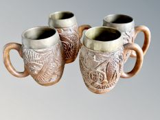 A group of four oriental carved wooden and brass tankards, tallest 14.