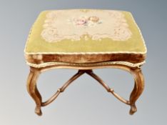An early 20th century carved beech footstool in tapestry fabric
