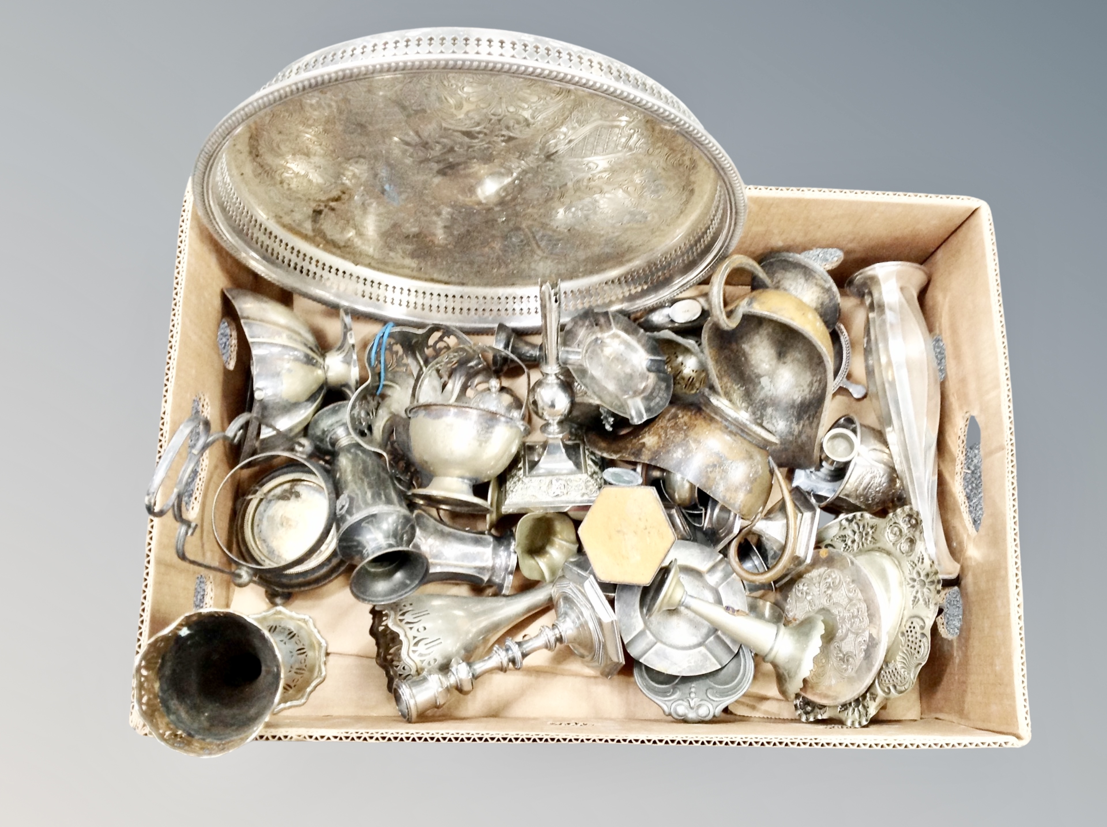 A box of silver plated wares including circular gallery serving tray, candlesticks, sauce boats etc.