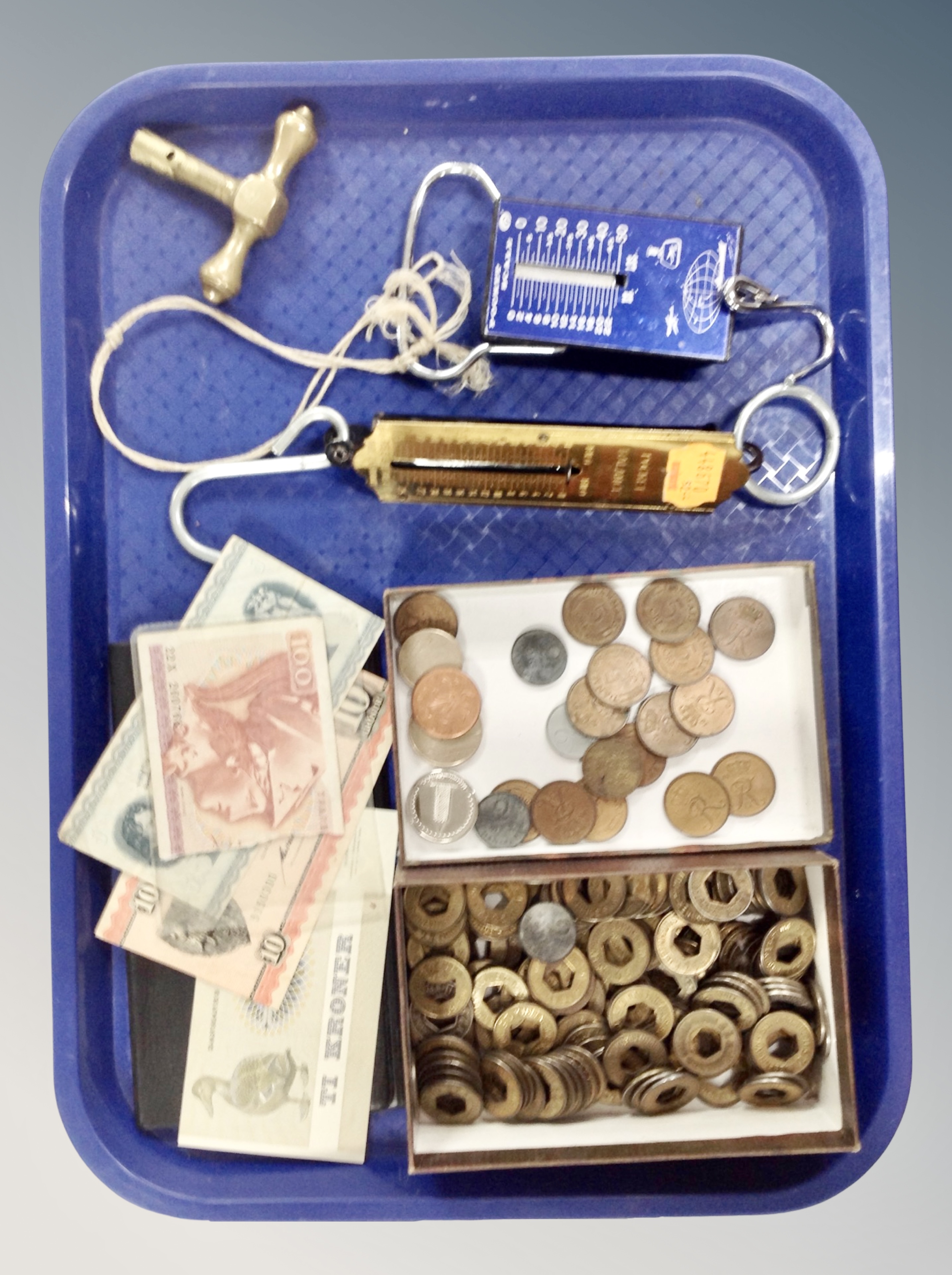 A tray containing pocket balance scales, foreign bank notes and coins.