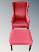 A Scandinavian wing backed armchair in red upholstery with matching stool