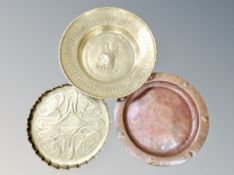 Two brass circular trays and a further hammered copper example.