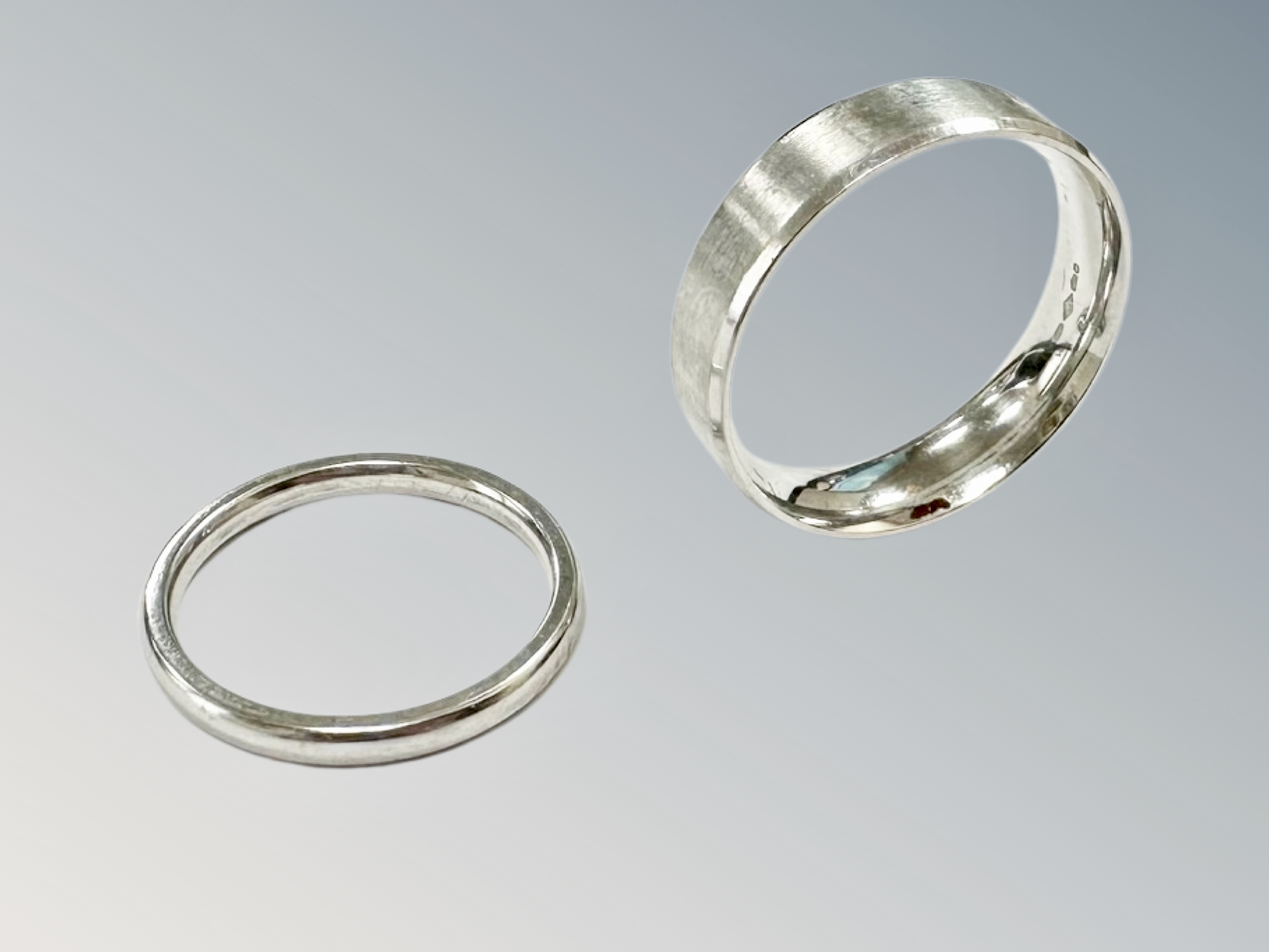 Two platinum band rings, the thinner ring size I½, the broader ring size O.