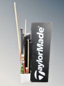 A group of snooker cues, hockey stick and a Taylor Made sign.