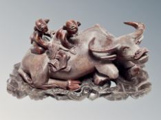 A 19th century Chinese carved hardwood group modelled as two figures astride a water buffalo on