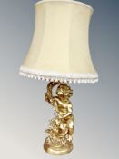 A gilt chalk cherub figural table lamp with tasselled shade