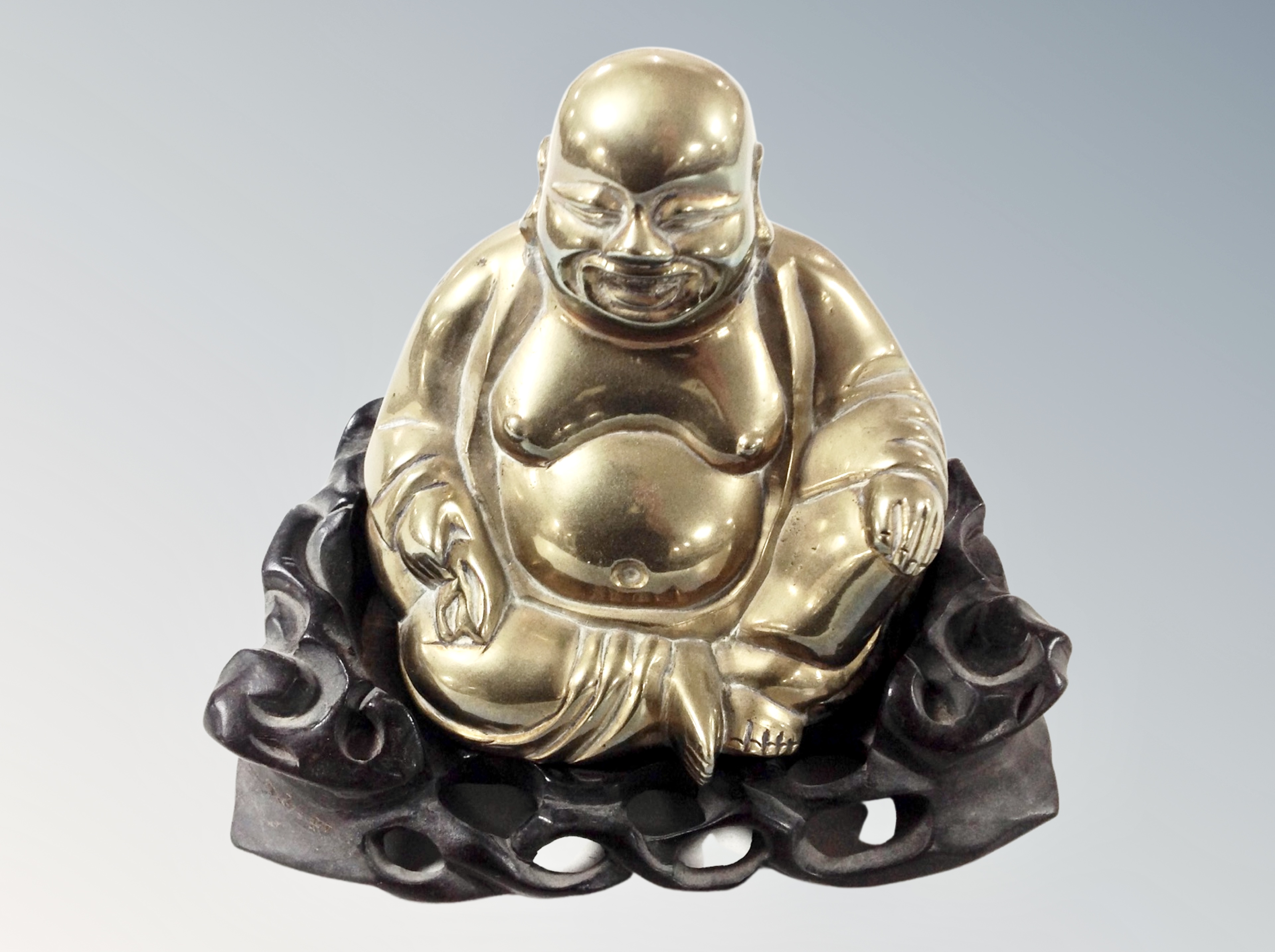 A Chinese cast brass figure of a seated Buddha on carved wooden base, overall height 14 cm.