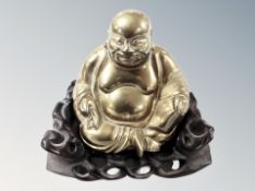 A Chinese cast brass figure of a seated Buddha on carved wooden base, overall height 14 cm.