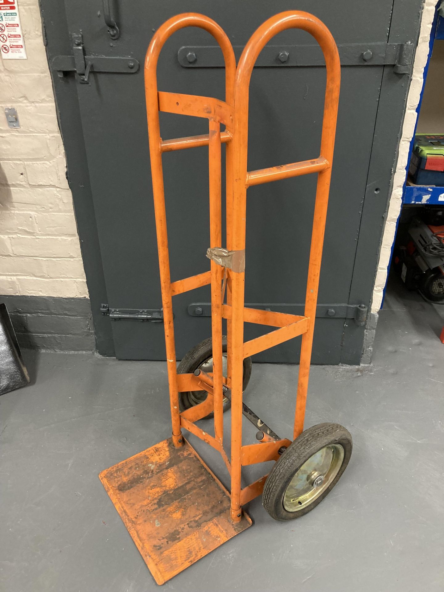 An orange spring-loaded sack barrow (af).