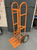 An orange spring loaded sack barrow (af).