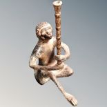 A cast metal figure of a seated monkey holding a staff,