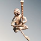 A cast metal figure of a seated monkey holding a staff,