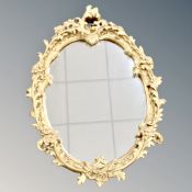 A contemporary ornate gilt gesso oval mirror, 66cm by 50cm.