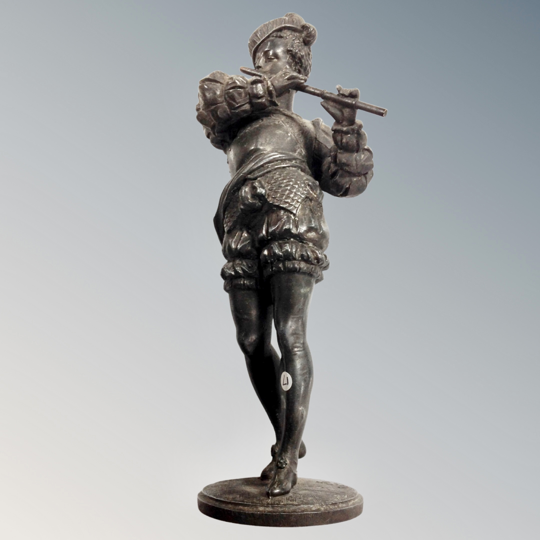 A cast iron figure of a man playing a flute,