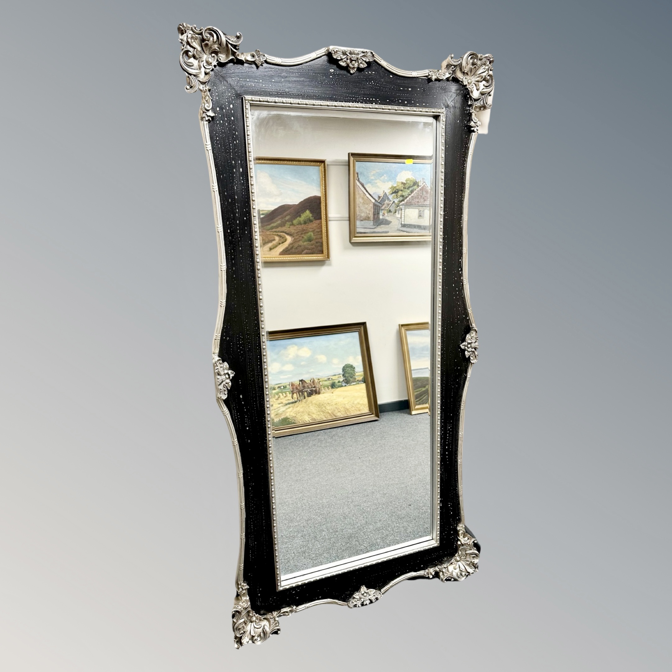An ornate silvered and ebonised mirror,