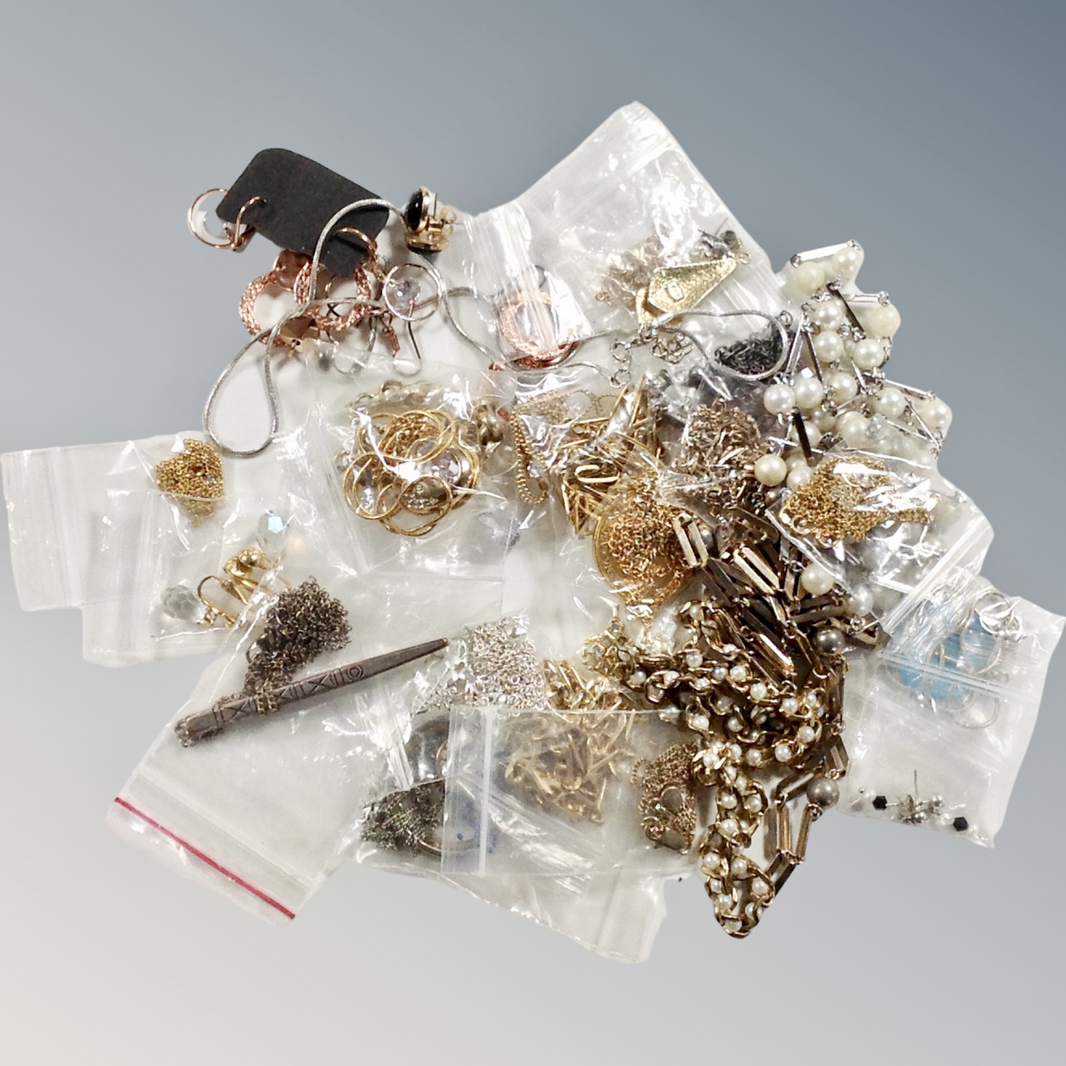 A box of numerous white and yellow metal necklaces and earrings