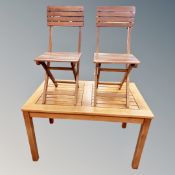 A teak garden table and two similar folding chairs