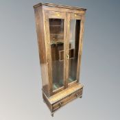 A glazed oak gun cabinet, with slots for five guns, three-division cartidge drawer beneath,
