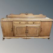 A 1930's carved oak sideboard on claw and ball feet,